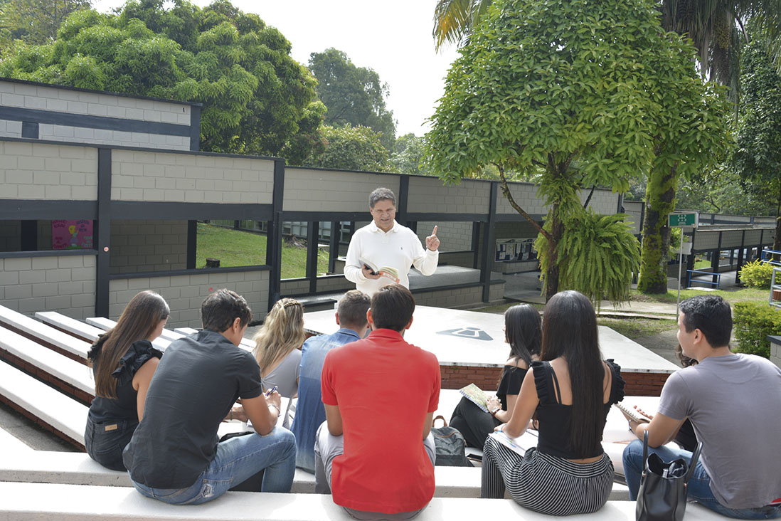 Imagen de cabecera para la Facultad de Humanidades, Artes y Ciencias Sociales de la Universidad de Ibagué en la foto se pueden ver personas alrededor de la media torta escuchando un profesor